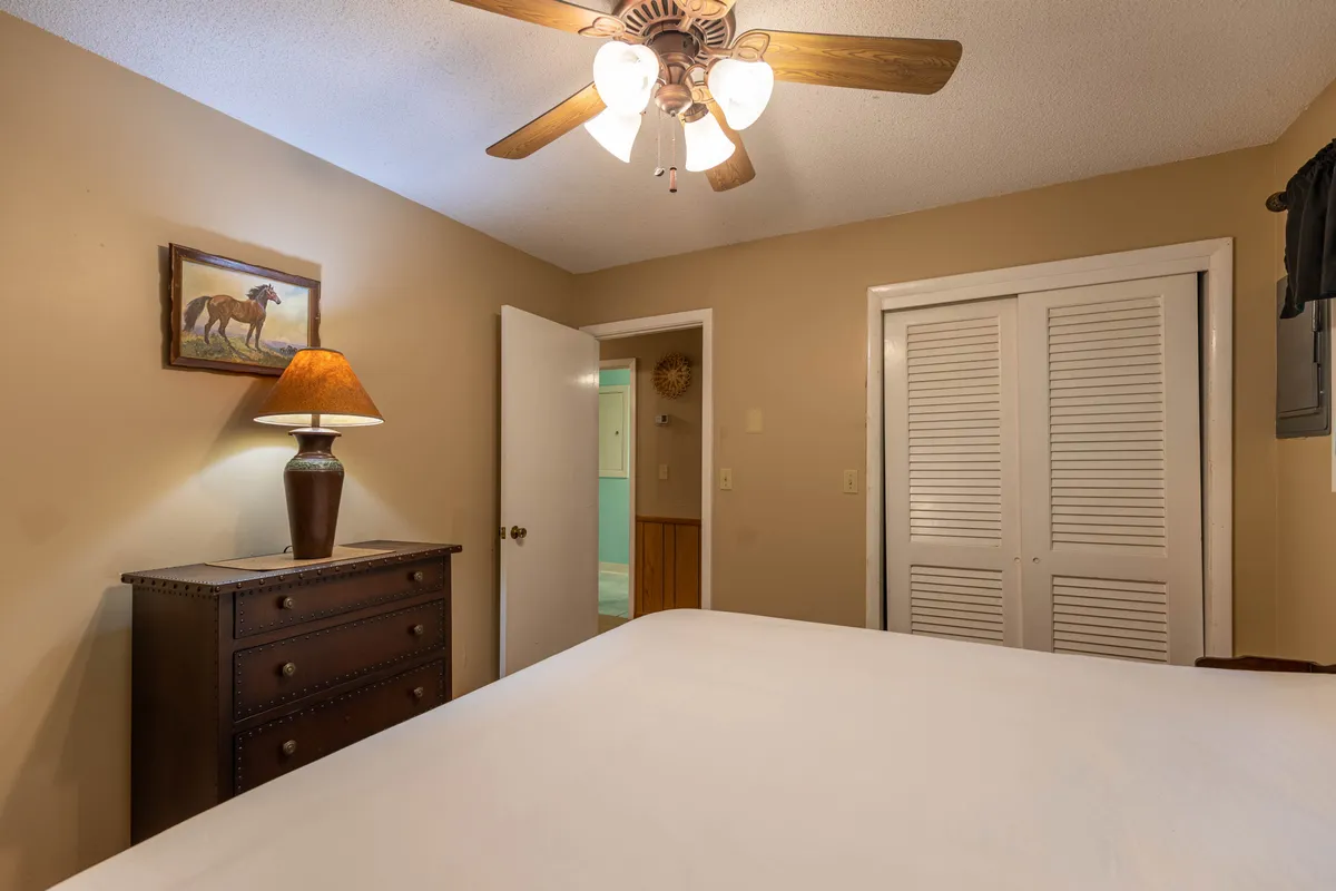 A tranquil bedroom scene featuring a neatly made bed, a soft-glowing lamp, a peaceful painting, and a dresser. The room feels calm and inviting, evoking restful sleep and relaxation—ideal for guests seeking a comfortable, allergy-safe retreat.
