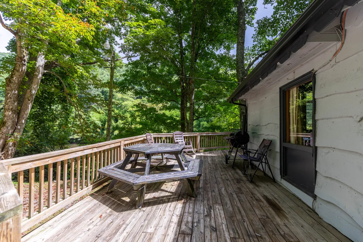 The wooden deck framed by outdoor furniture and surrounded by trees invites outdoor dining, relaxing, and evening barbecues. The deck's setup hints at shared meals and family moments, while views of the surrounding nature connect the image to the broader outdoor adventure theme.