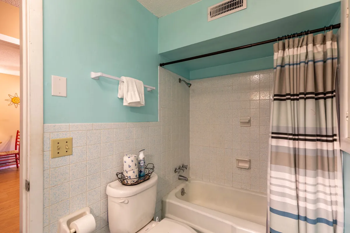 A clean, modern bathroom with a bathtub, toilet, shower curtain, and towel rack. The space is tidy and fresh, with light tones and functional amenities that suggest relaxation and comfort for guests after a day of adventure.
